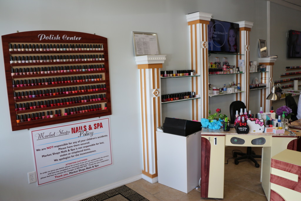 Wall-mounted shelves with an assortment of different nail polishes on it at Market Shops Nails and Spa in Sandestin, Florida.