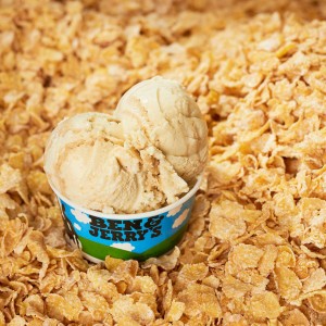 A small cup of Ben and Jerry's ice cream sitting on a bed of frosted flakes cereal.